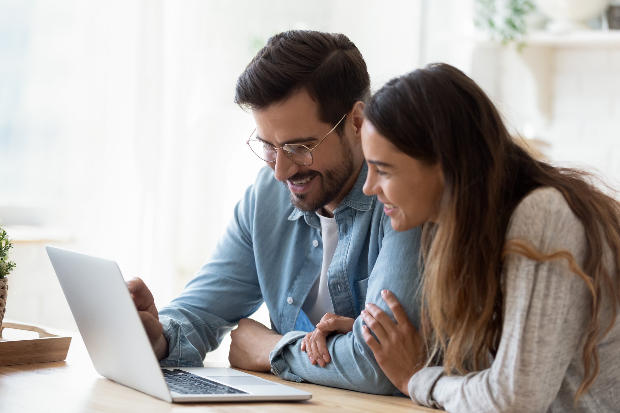 A couple looking at a laptop screen, smiling.