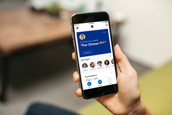 Person holding a phone using the PayPal app
