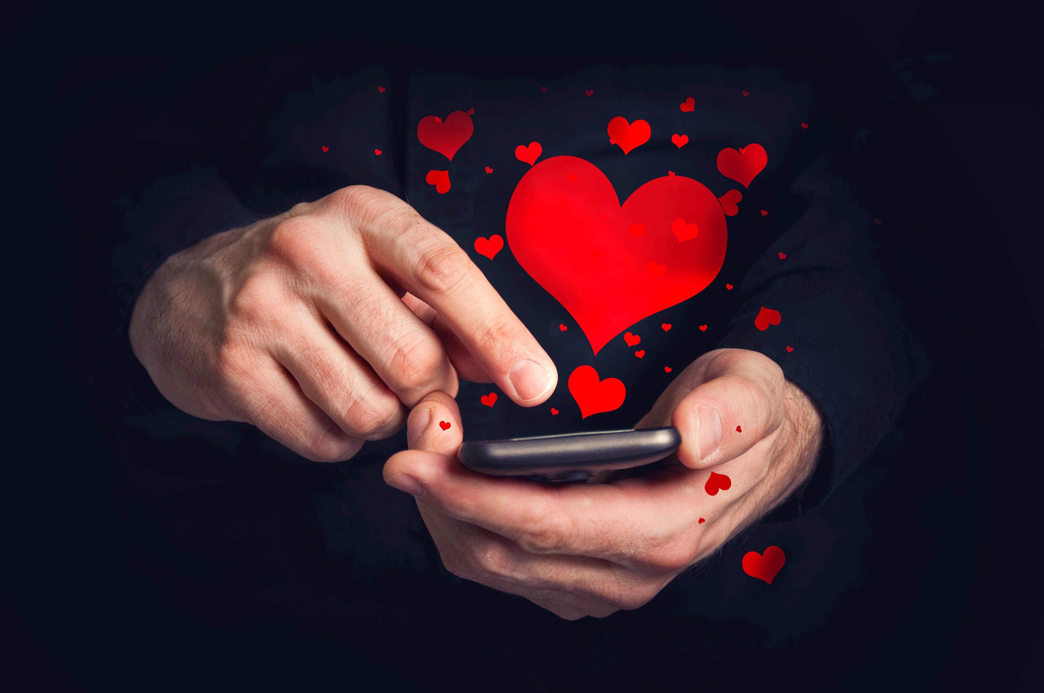Illustrated hearts hover above someone using a smartphone.