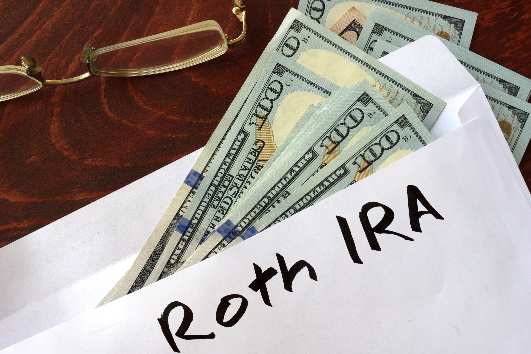 Envelope with hundred-dollar bills sticking out of it labeled Roth IRA