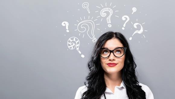 A woman looking up over her head at question marks, superimposed above. 