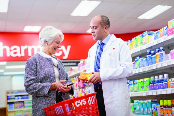 A CVS pharmacist helping an elderly woman pick out healthcare products.