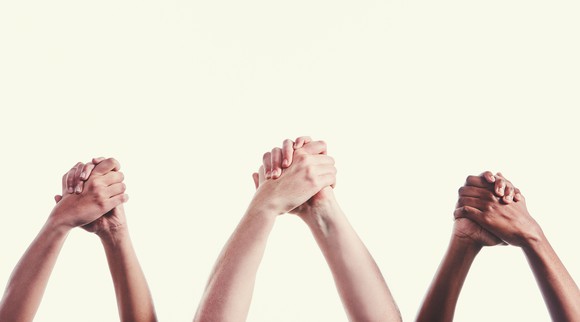 Three pairs of hands clasped together. 