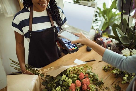 Woman paying for purchase using mobile wallet on phone