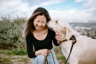 a dog kissing a girl's head