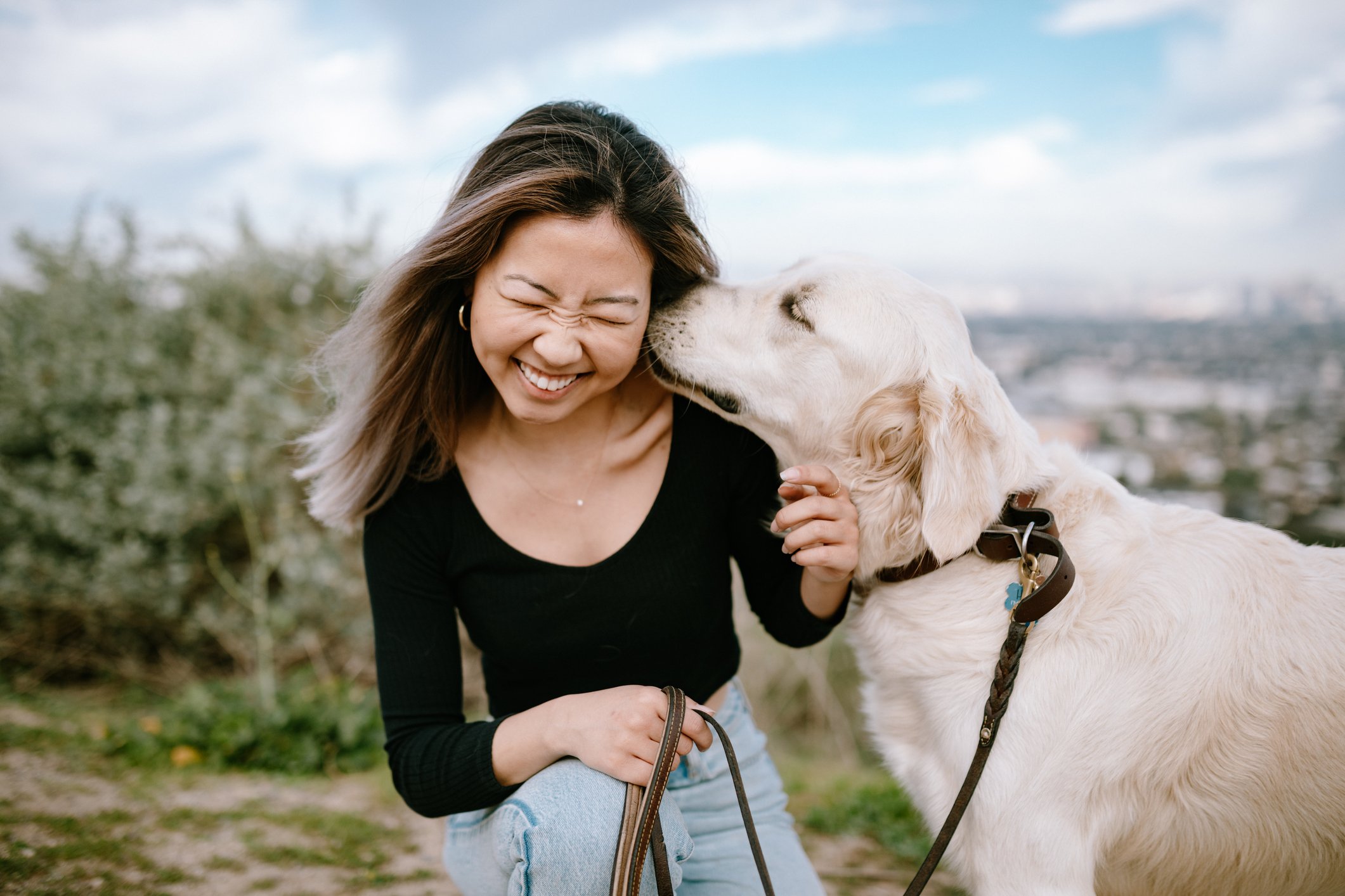 A dog kissing a girl's head outdoors
