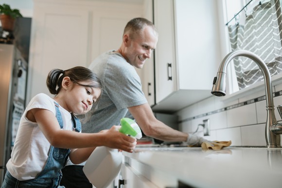 A father and daughter cleaning in their kitchen.