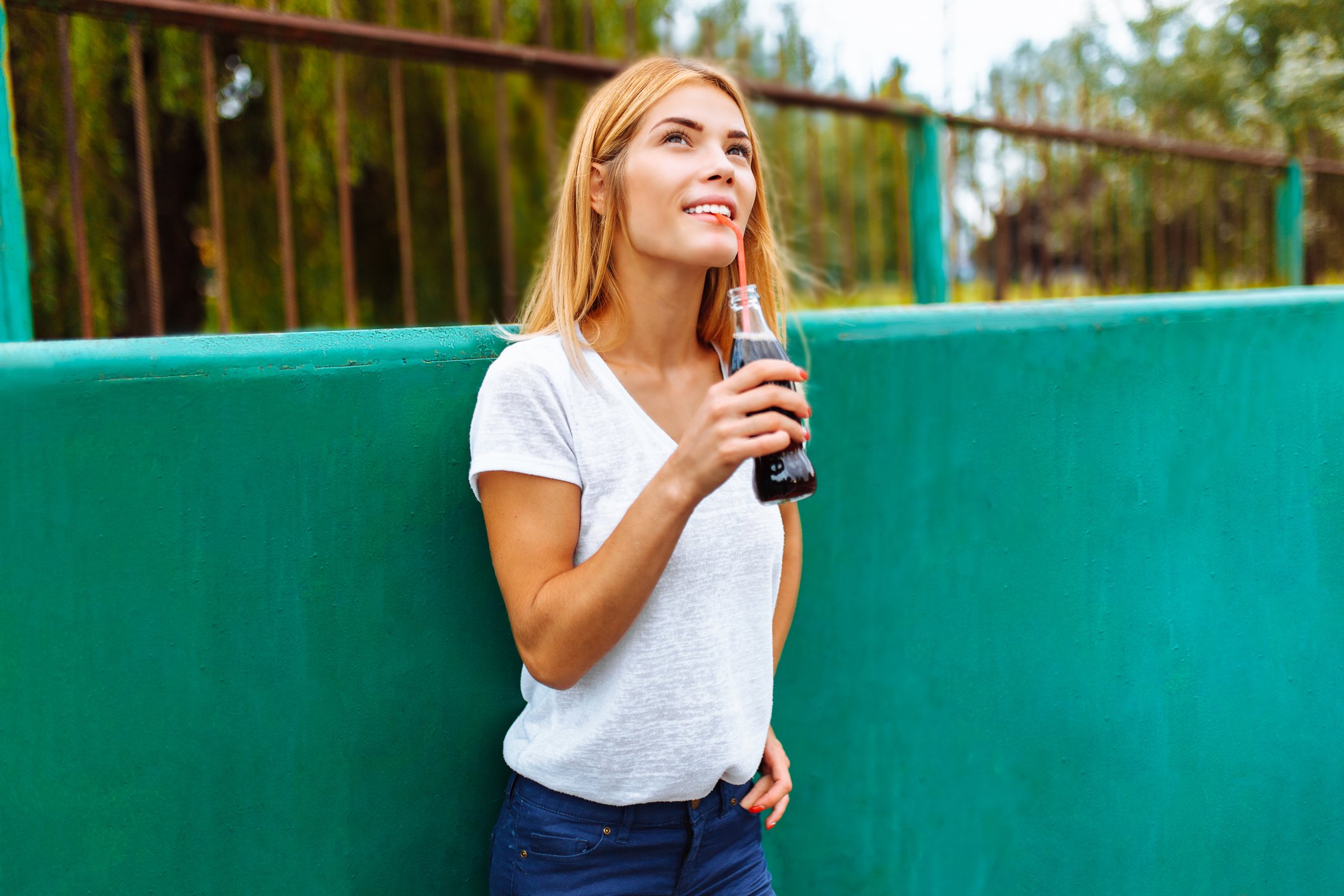 A woman drinking a bottle of cola.