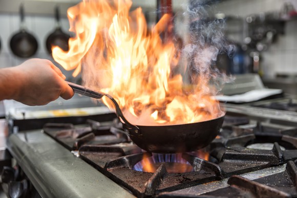 Pan on fire on a stove.