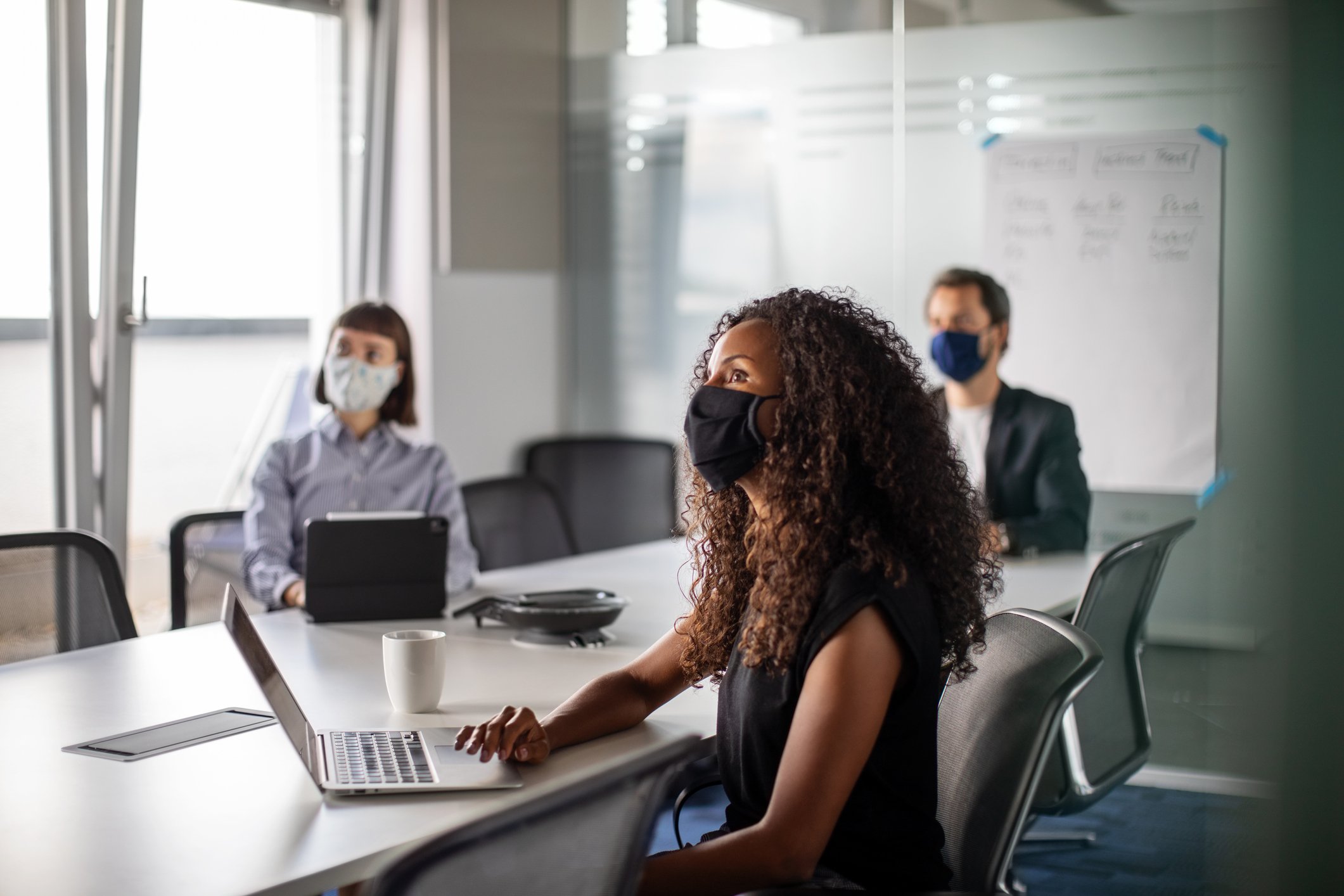 Workers in an office wearing masks during a meeting