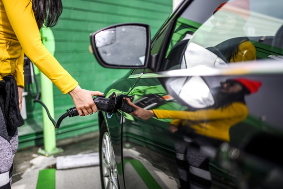 Woman plugging charger into electric vehicle.