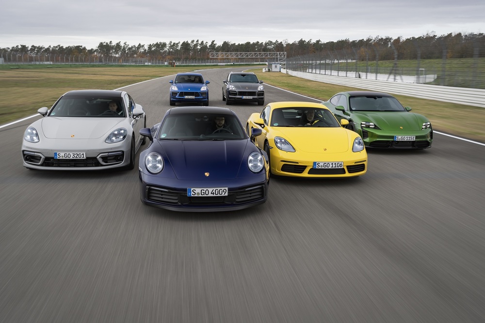 A line of Porsche vehicles driving.