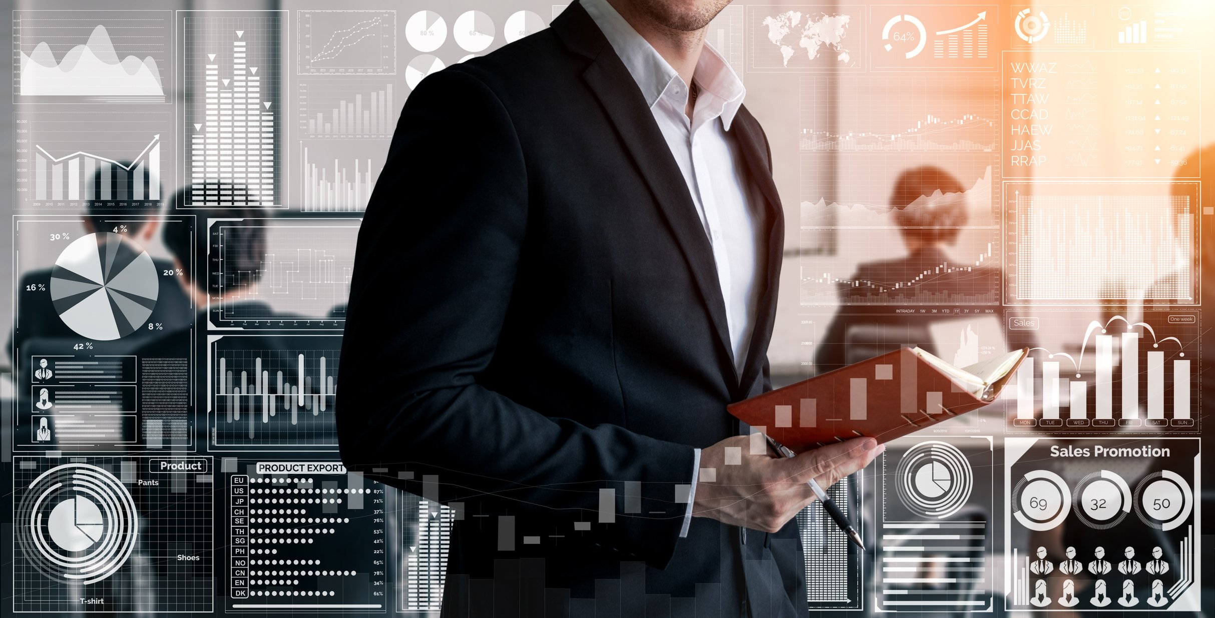 Man in business casual dress seen from neck-down with book open and graphs and charts animations all around him in a conference room. 