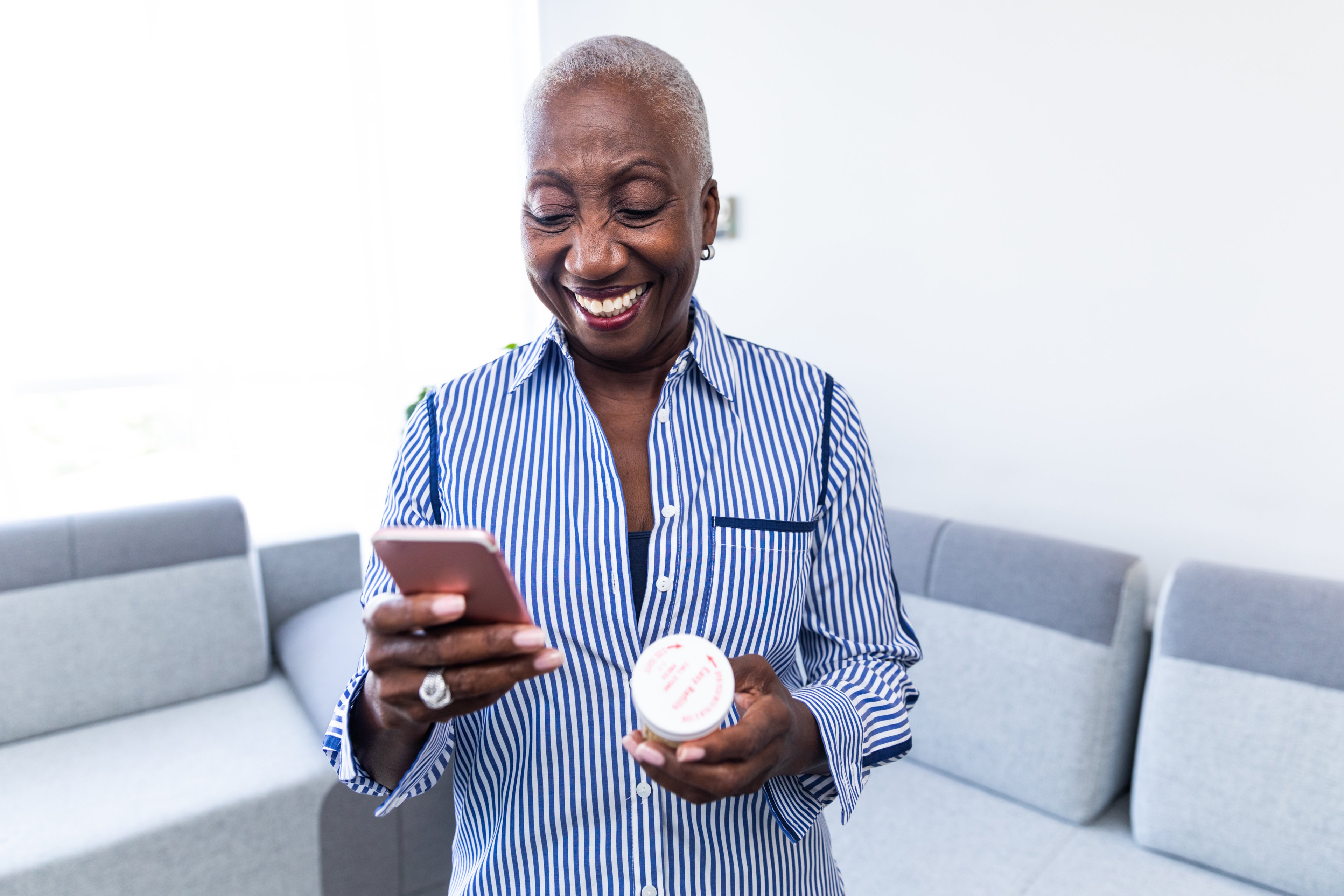 A woman holding a prescription bottle and a phone.
