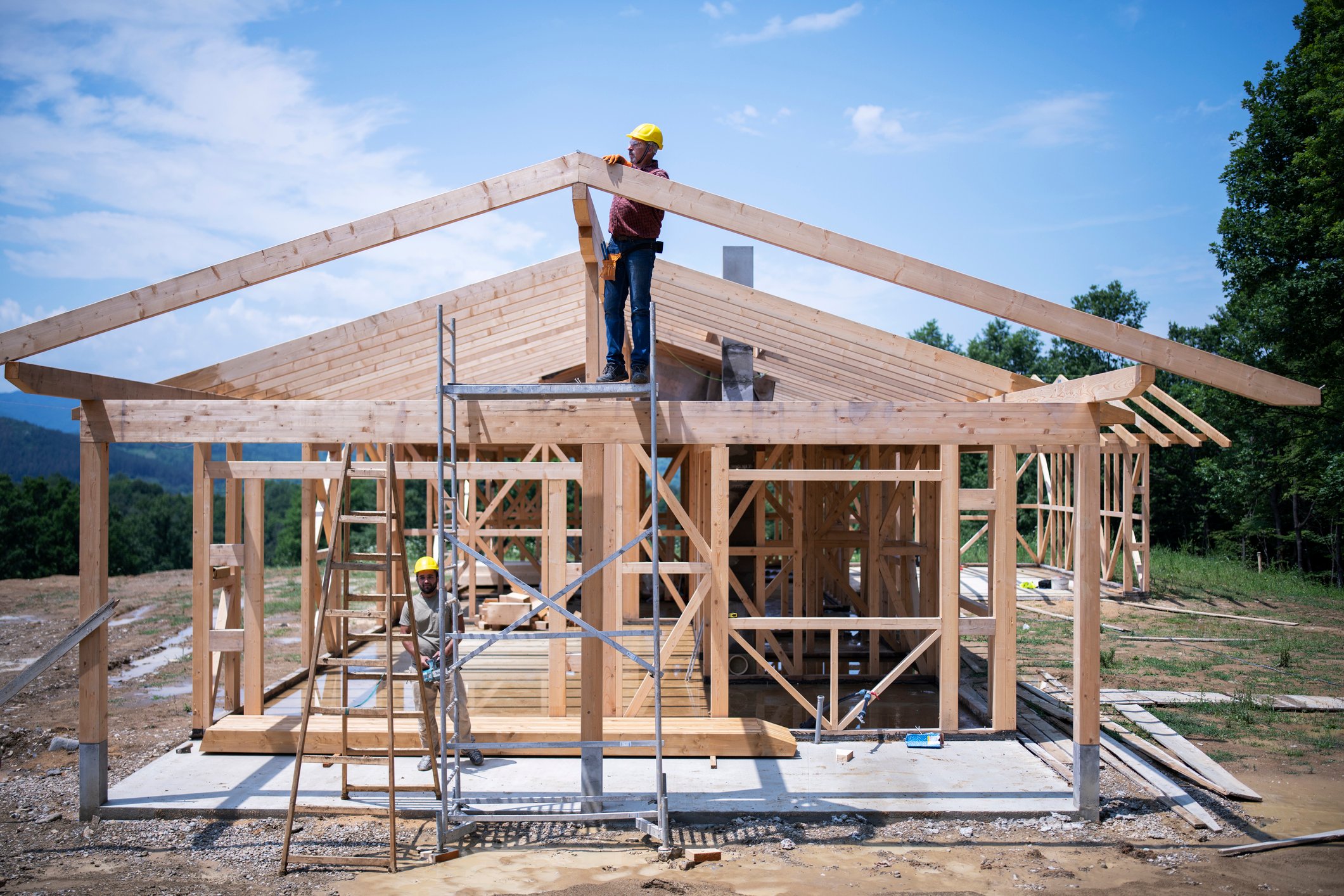 A house frame with a worker nailing in a piece of wood.