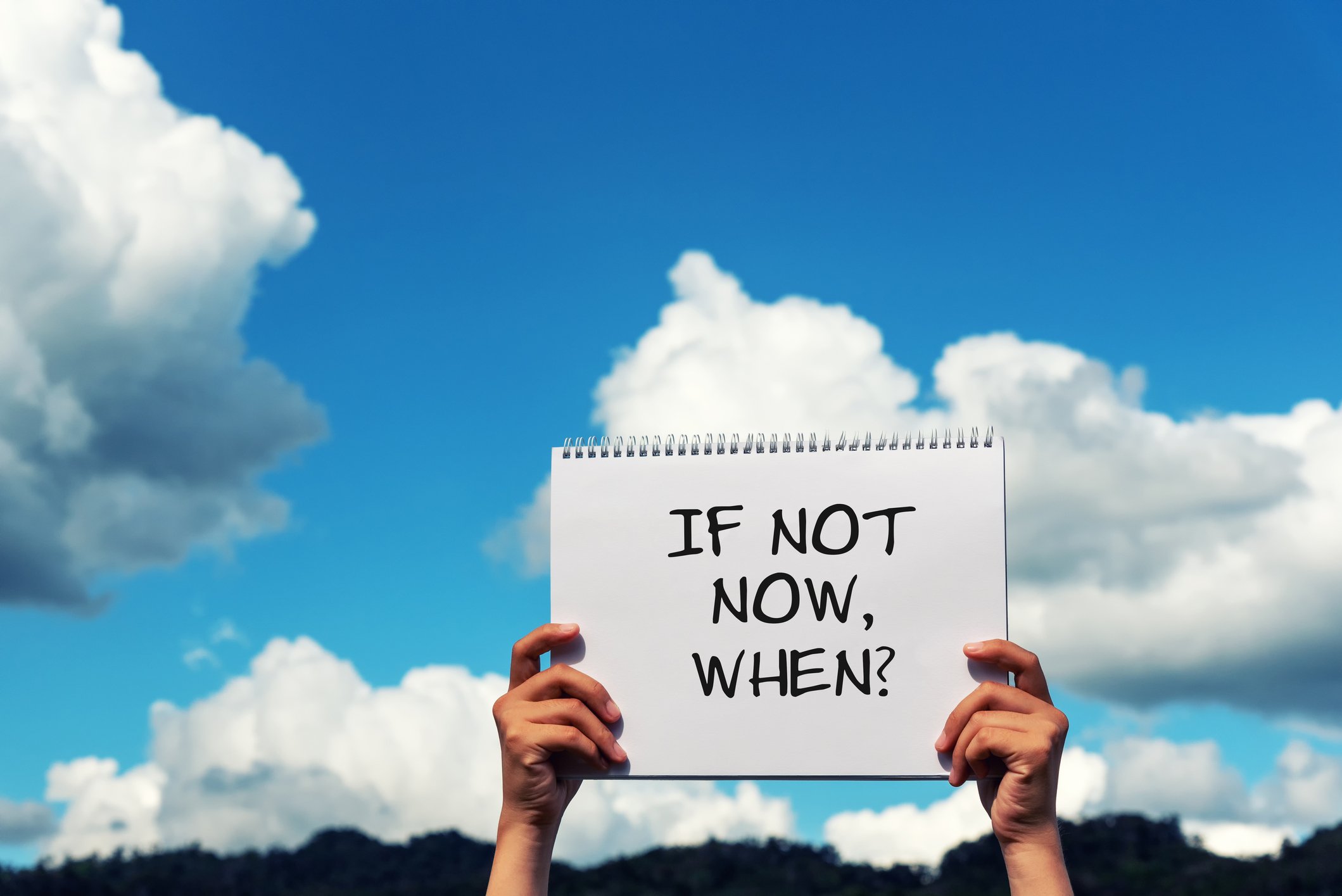 Hands holding up sign that says If Not Now, When? 
