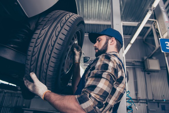 Man putting a tire on a car
