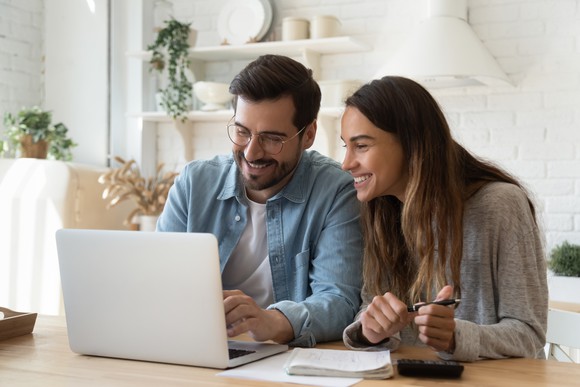 A couple looking at a laptop, happy about a purchase.