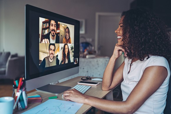 A young woman chats to her friends on a video conferencing platform.