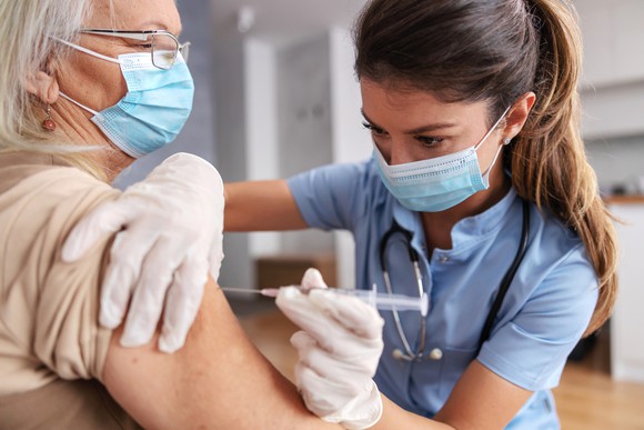 A nurse vaccinates a woman with a coronavirus vaccine.