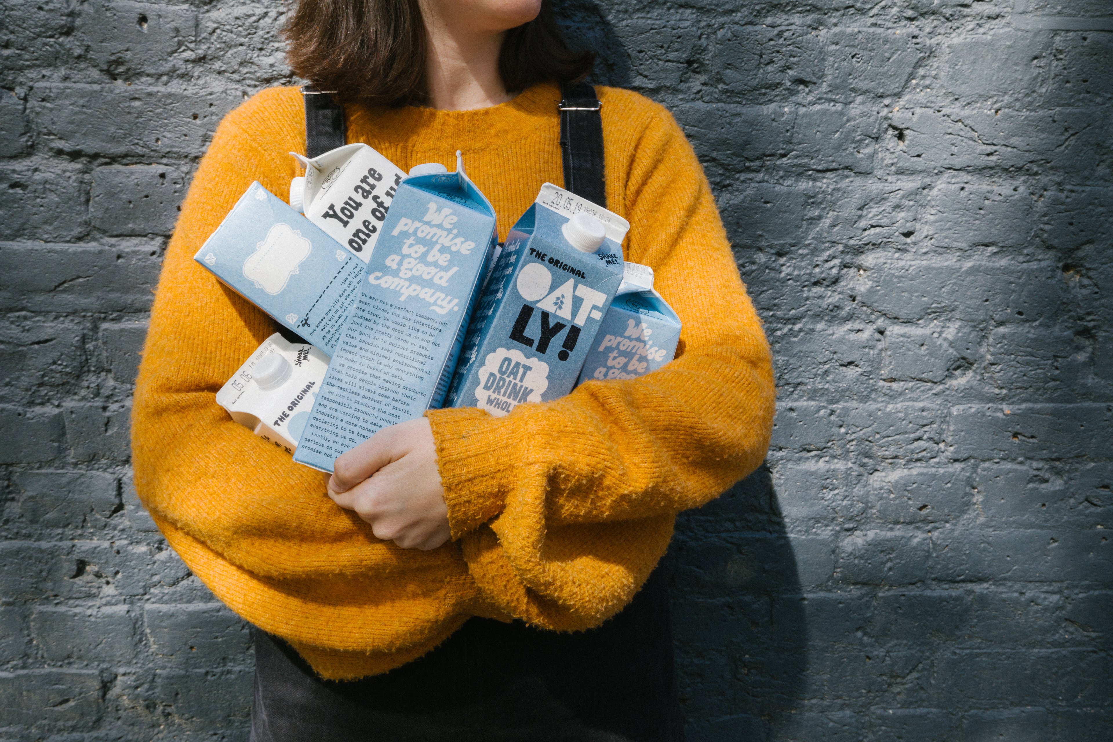 A woman holding cartons of Oatly oat milk.