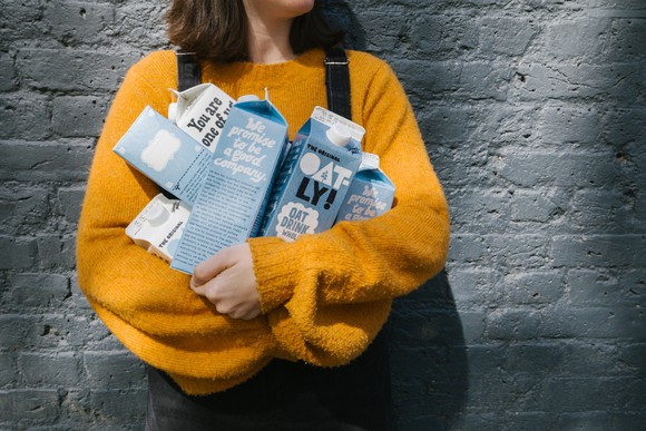 A woman holding cartons of Oatly oat milk.