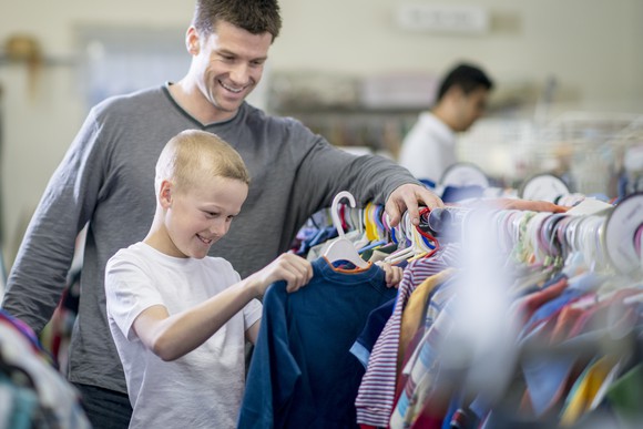 A man and child smiling while looking at shirts.