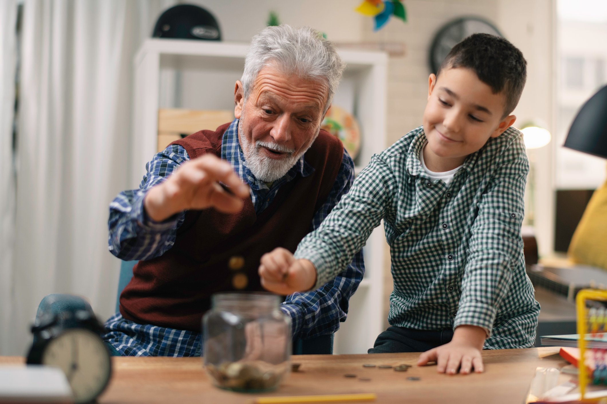 Senior man and young boy putting change in jar 