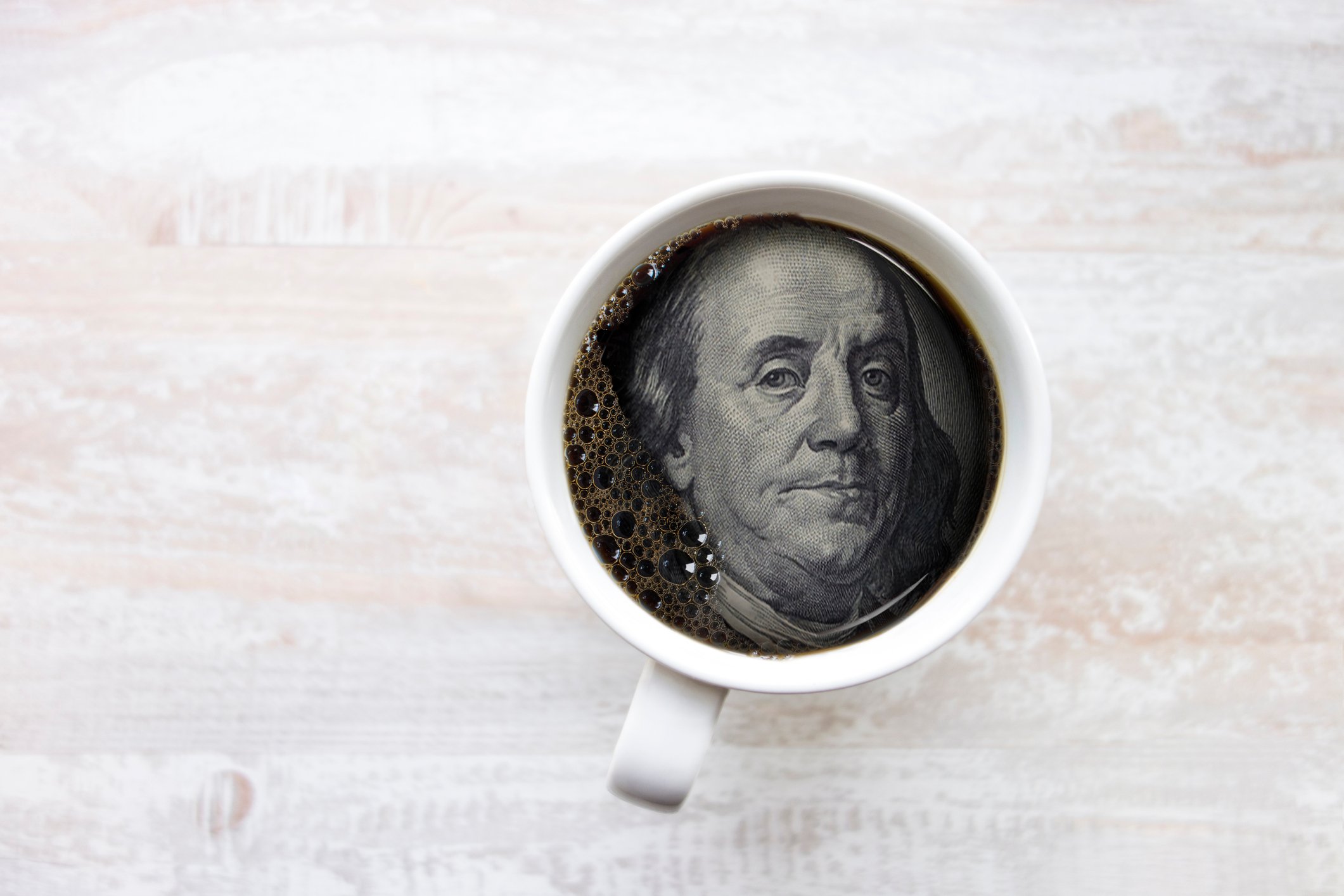 Ben Franklin's face from hundred dollar bill in coffee cup