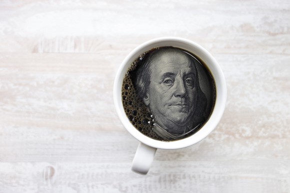 Ben Franklin's face from hundred dollar bill in coffee cup
