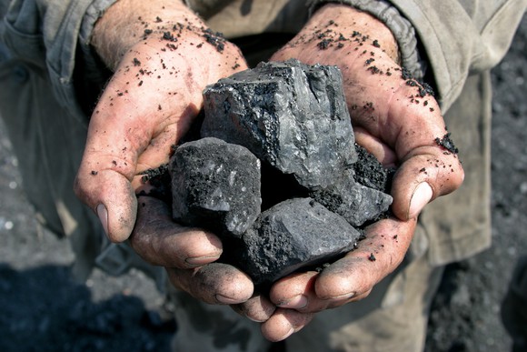 Person holding coal in hands. 