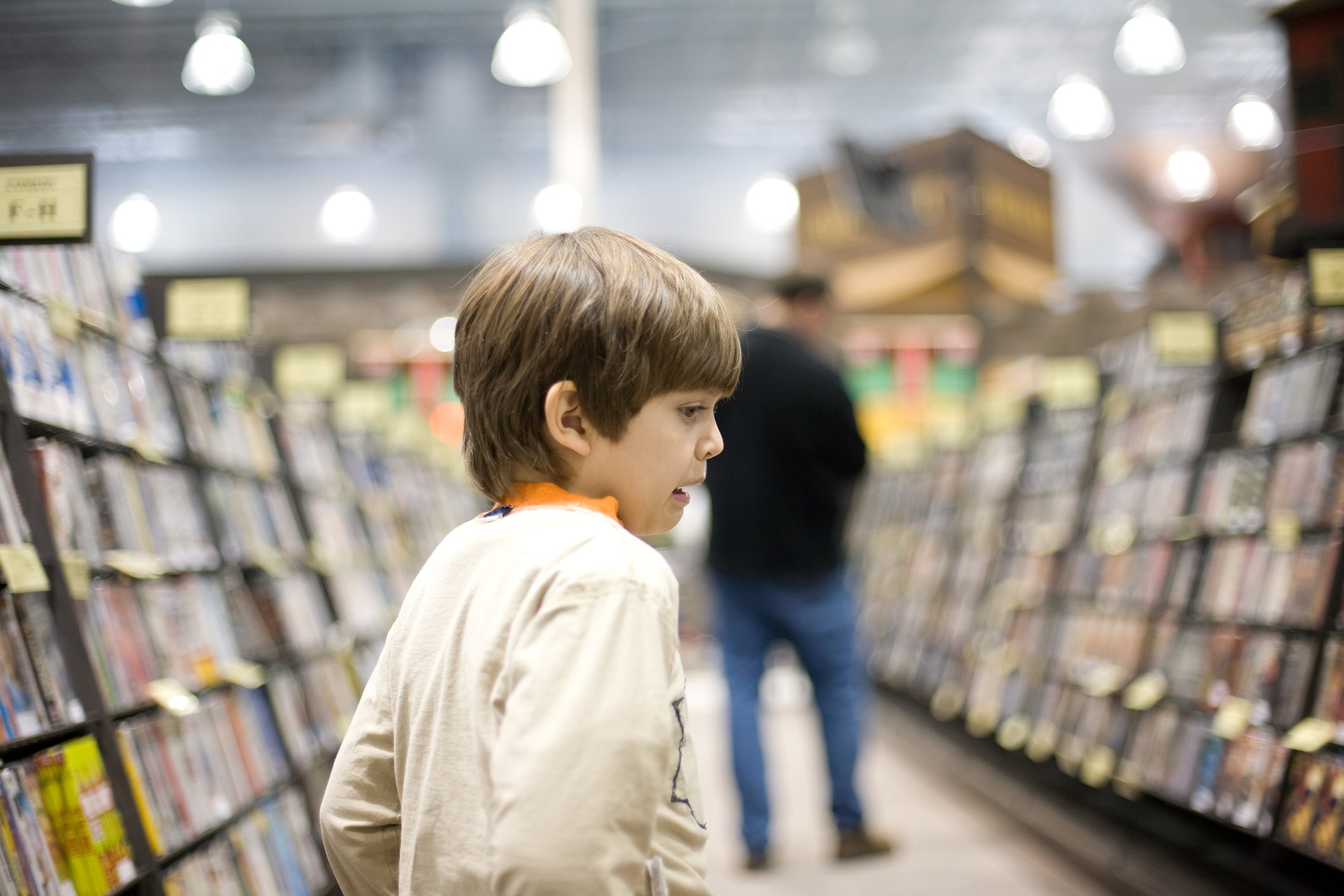 Boy inside a store looking at shelves of video game titles.