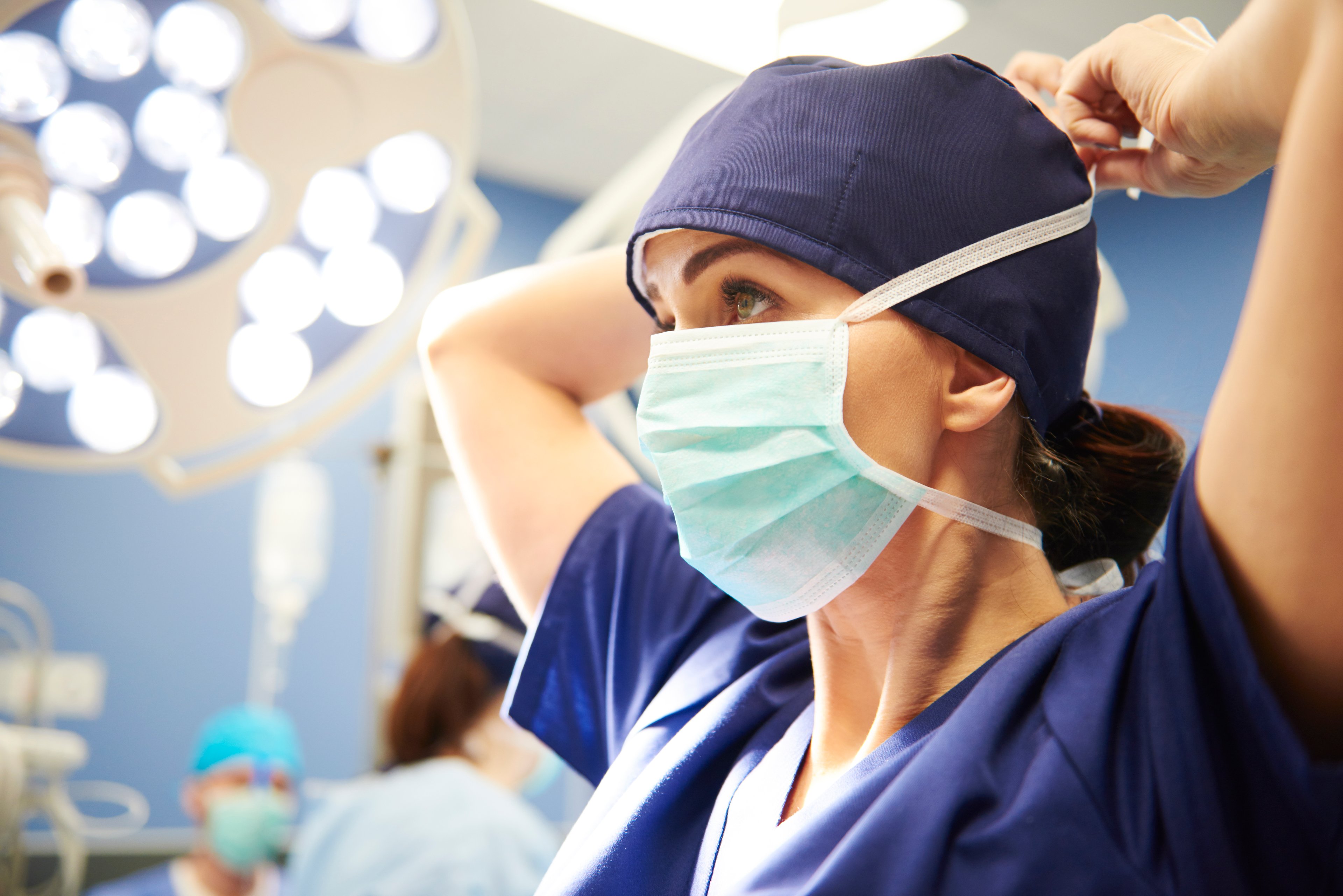 Woman putting on  surgical mask in operating room