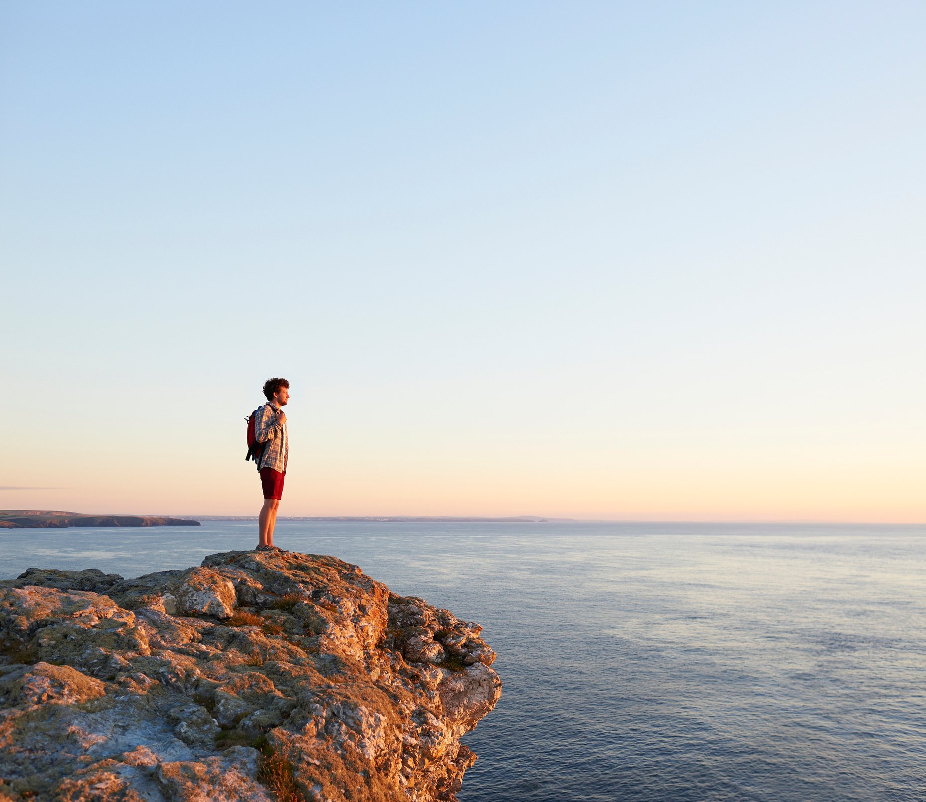 A man standing on a cliff overlooking the ocean