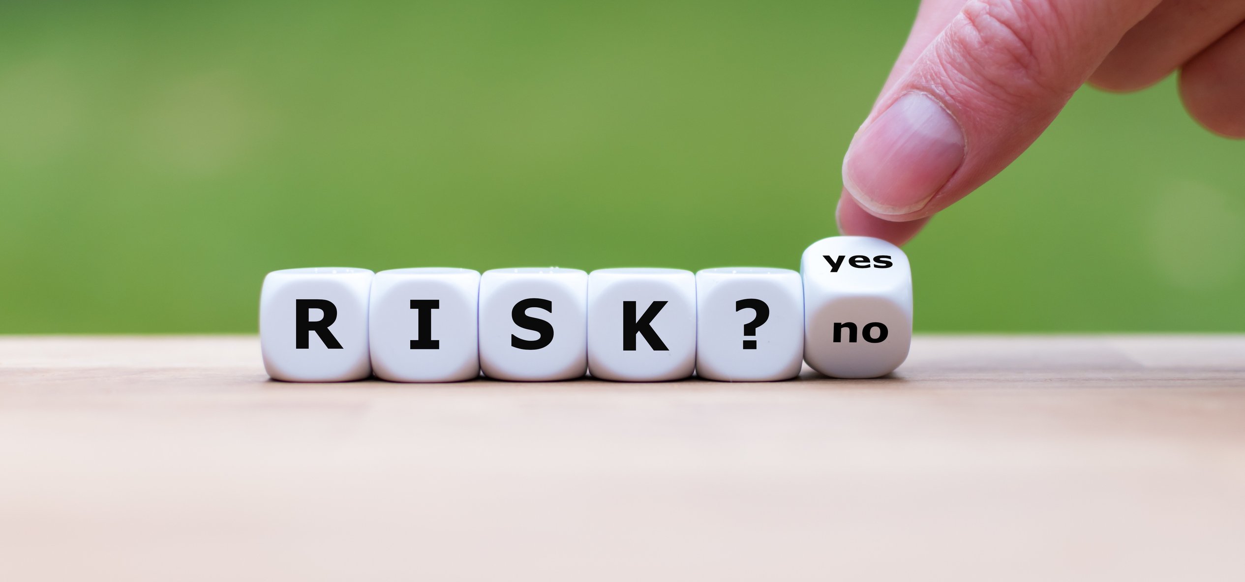 dice saying risk with fingers flipping final die between yes and no