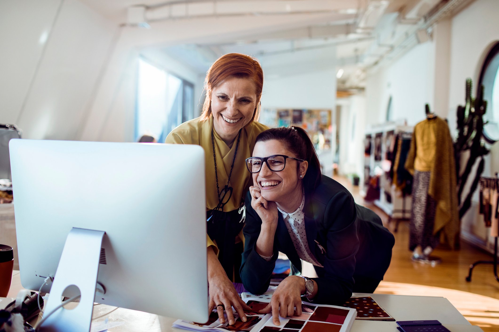 Two women in a fashion studio at a computer.