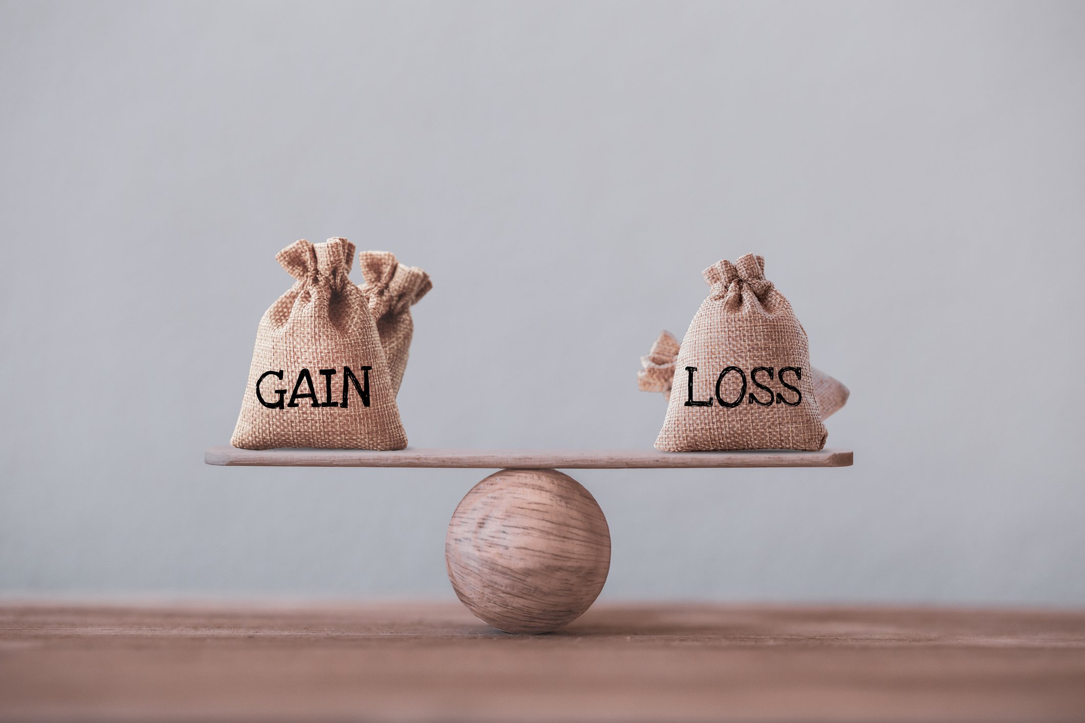 Burlap bags labeled gain and loss are balanced on a scale. 