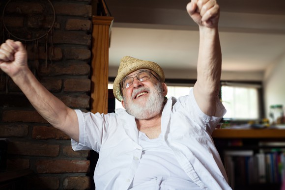 A happy older man is smiling, with arms outstretched.