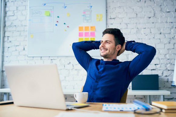 A man relaxes behind the screen of a laptop.