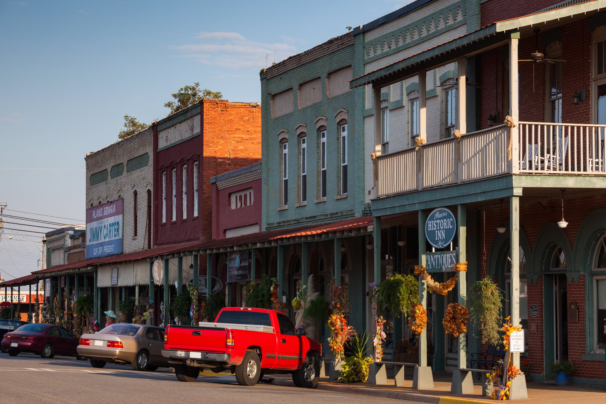 Main street in a small American town with stores, a red pickup truck, and several cars.