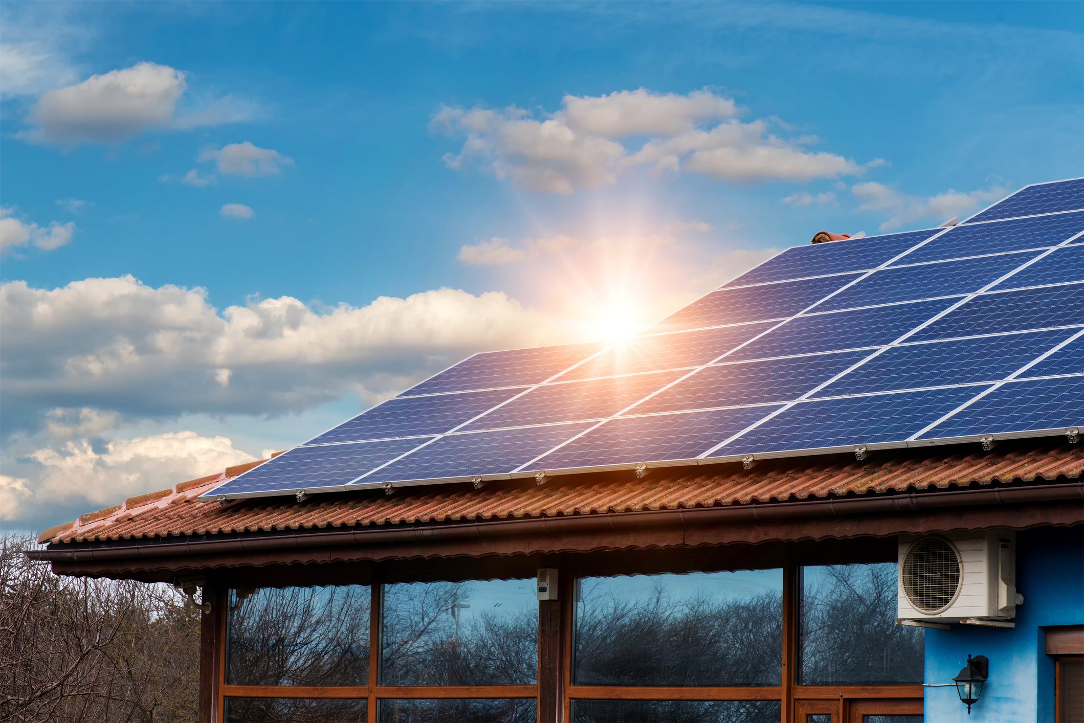 Roof with solar panels and a setting sun in the background. 