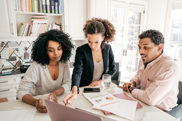 Three people looking at spreadsheets and charts 