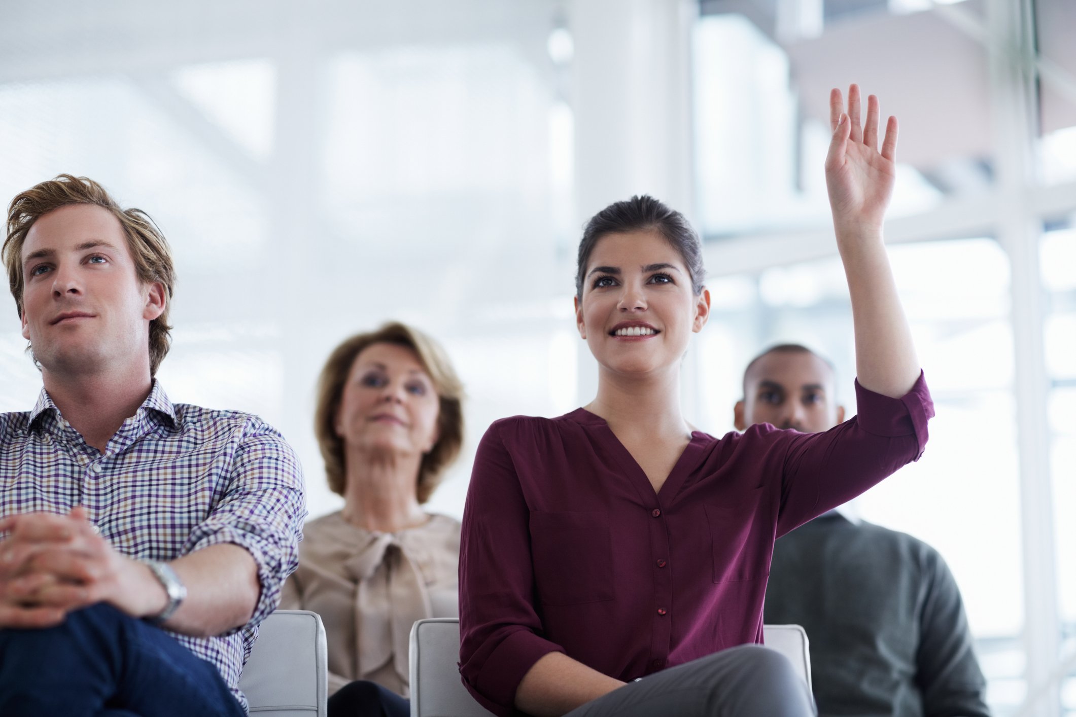 Woman sitting in classroom with her hand raised 
