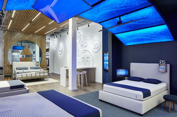Sleep Number retail showroom with beds under a canopy of bright blue panels.