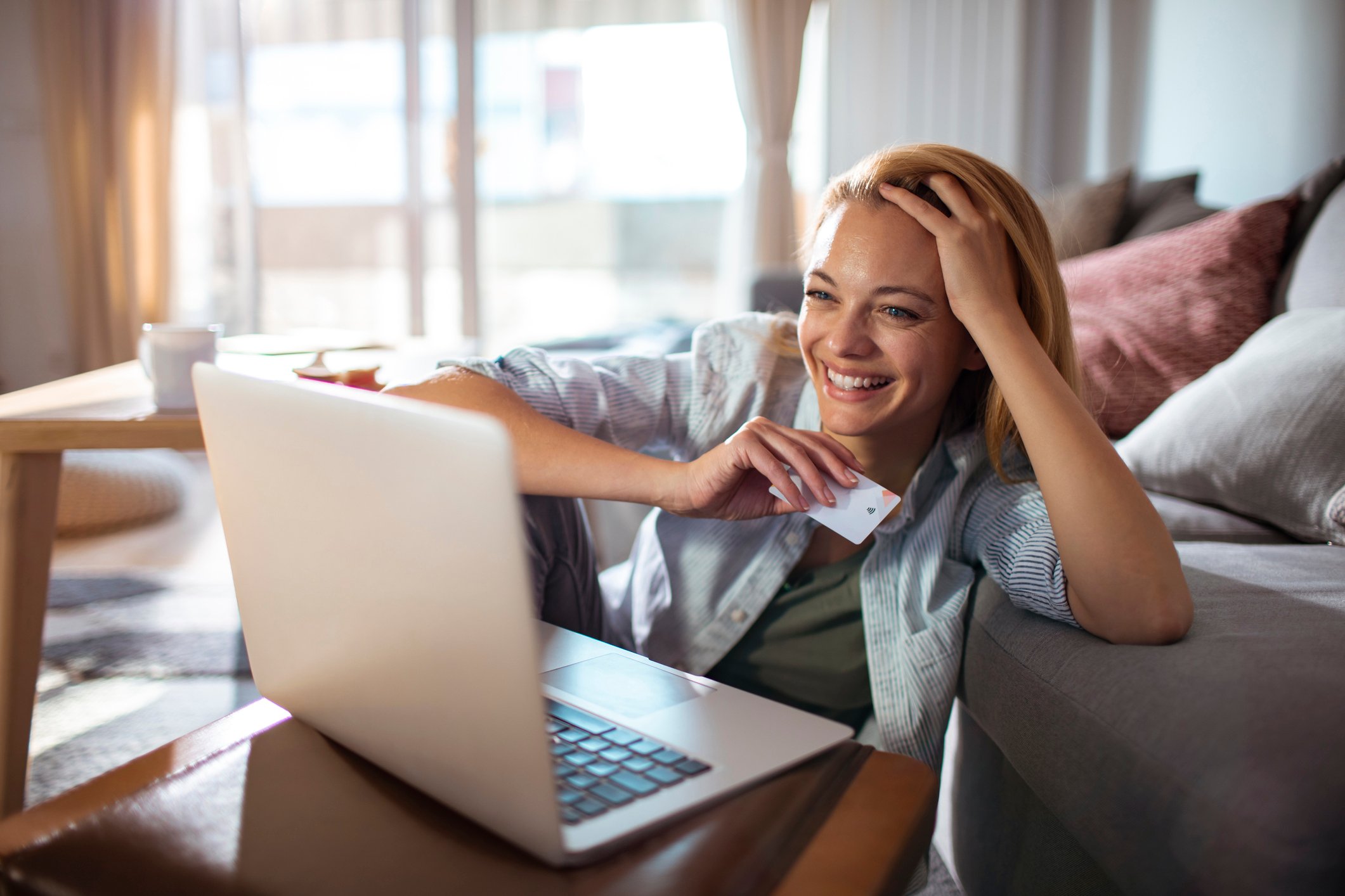 A woman smiles as she shops online using her laptop.