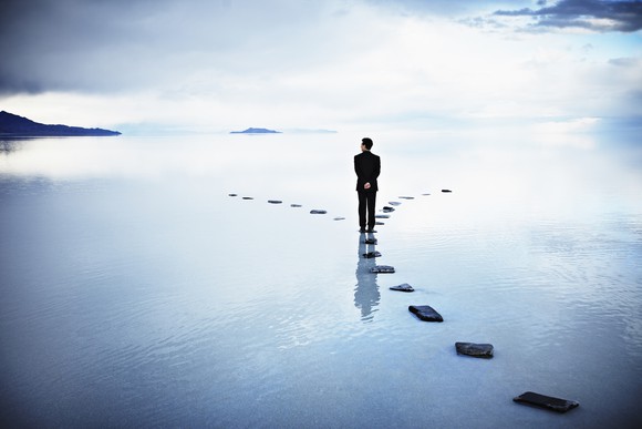 A businessman standing at a stoned pathway.