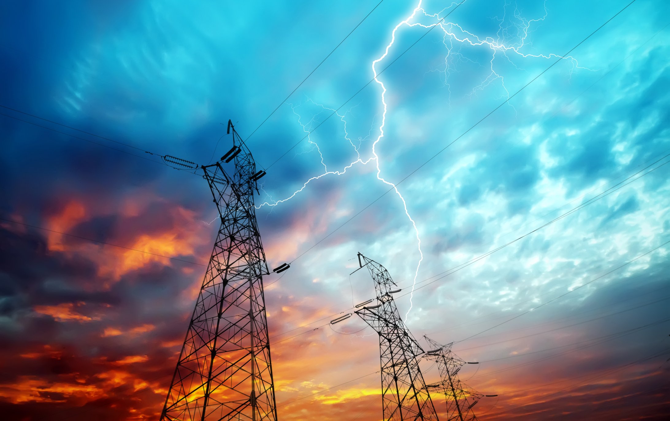 Electric lines with lightning in the background.