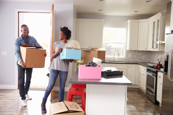 Young couple moving boxes into apartment