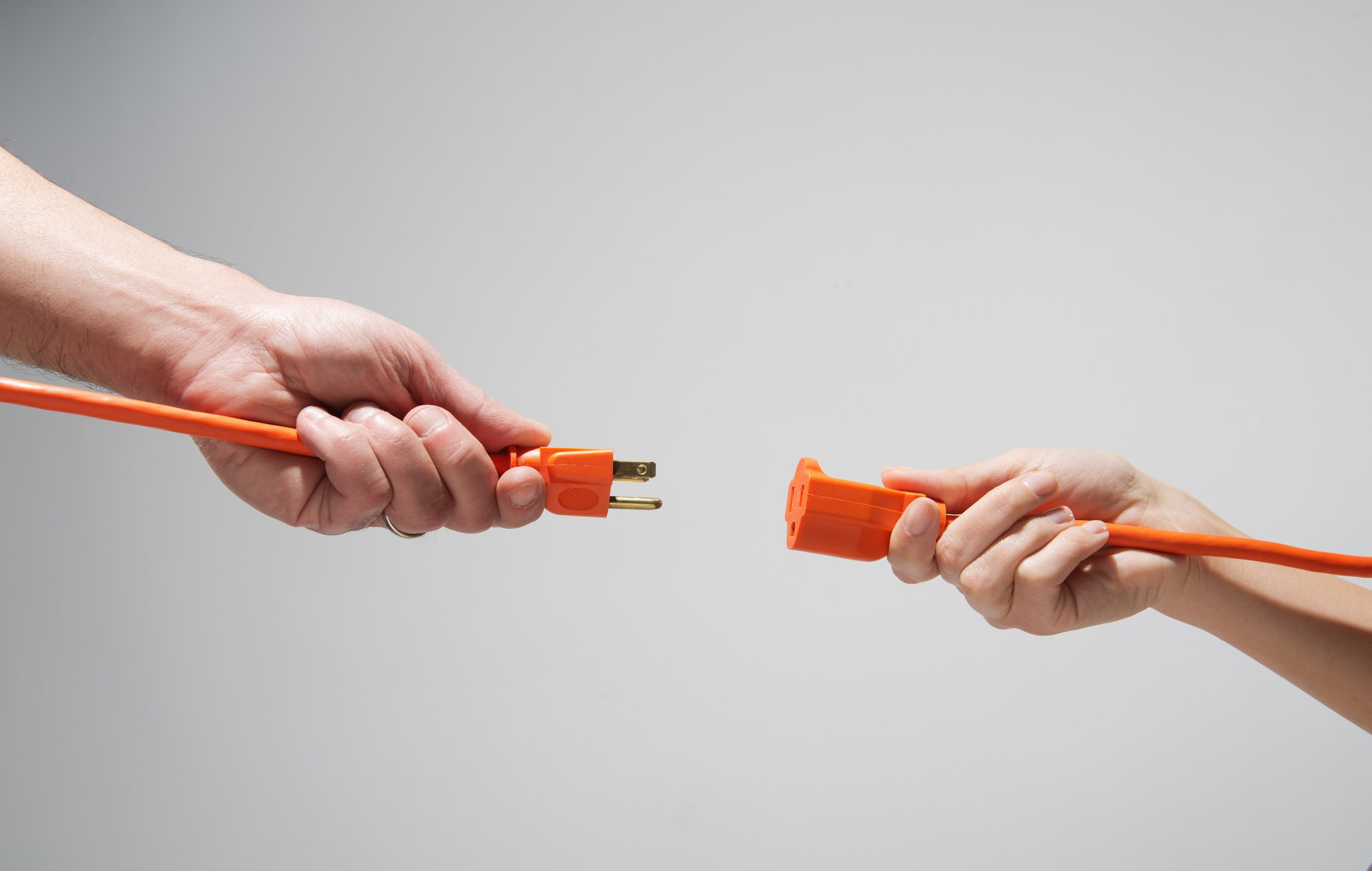 Two hands connecting extension cords.