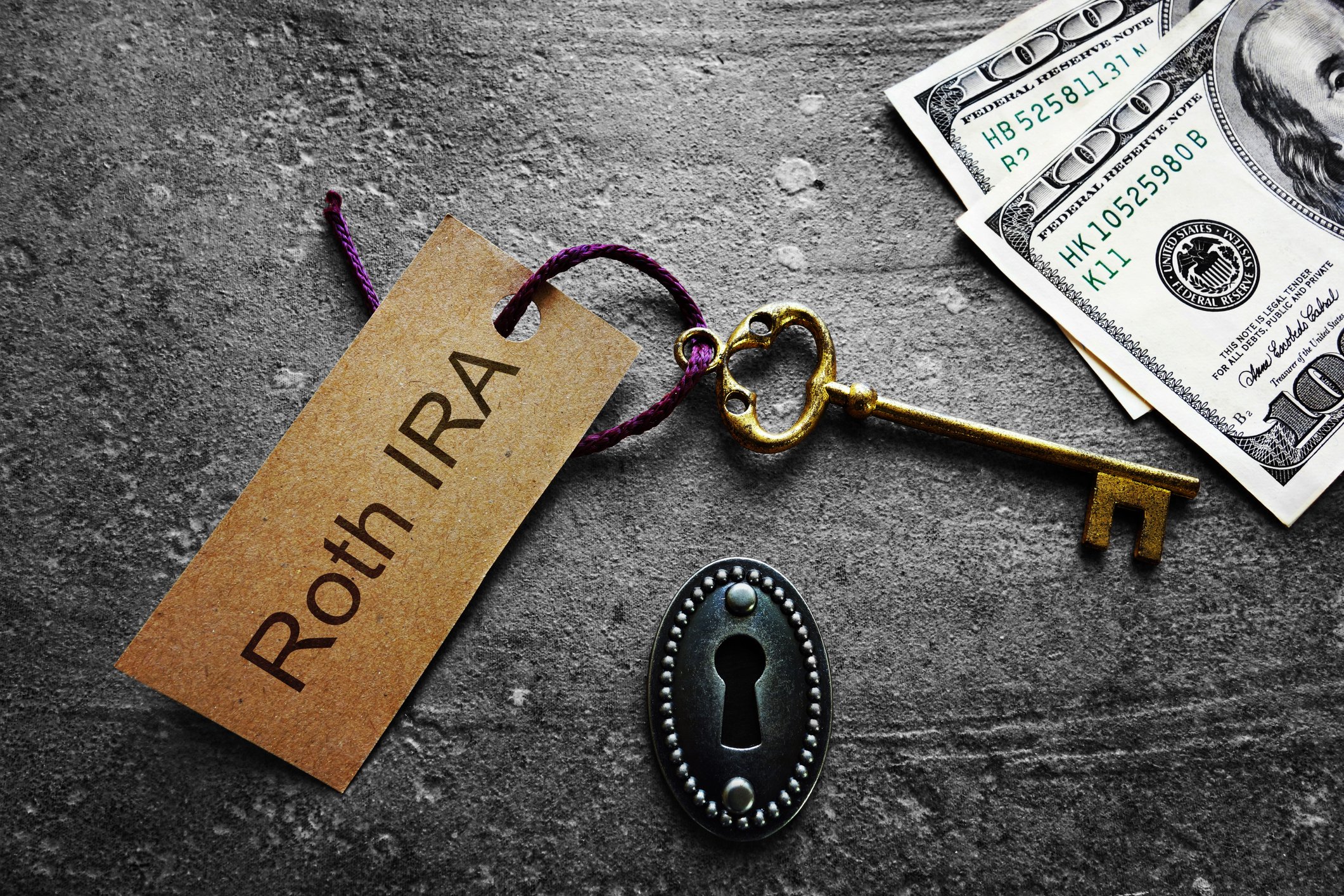Gold key with Roth IRA tag, with keyhole and cash.